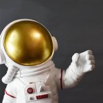 Kosmonautfigur i dekorativ stil med gyllene hjälm och vit dräkt, idealisk för vetenskaplig och rymddekoration.