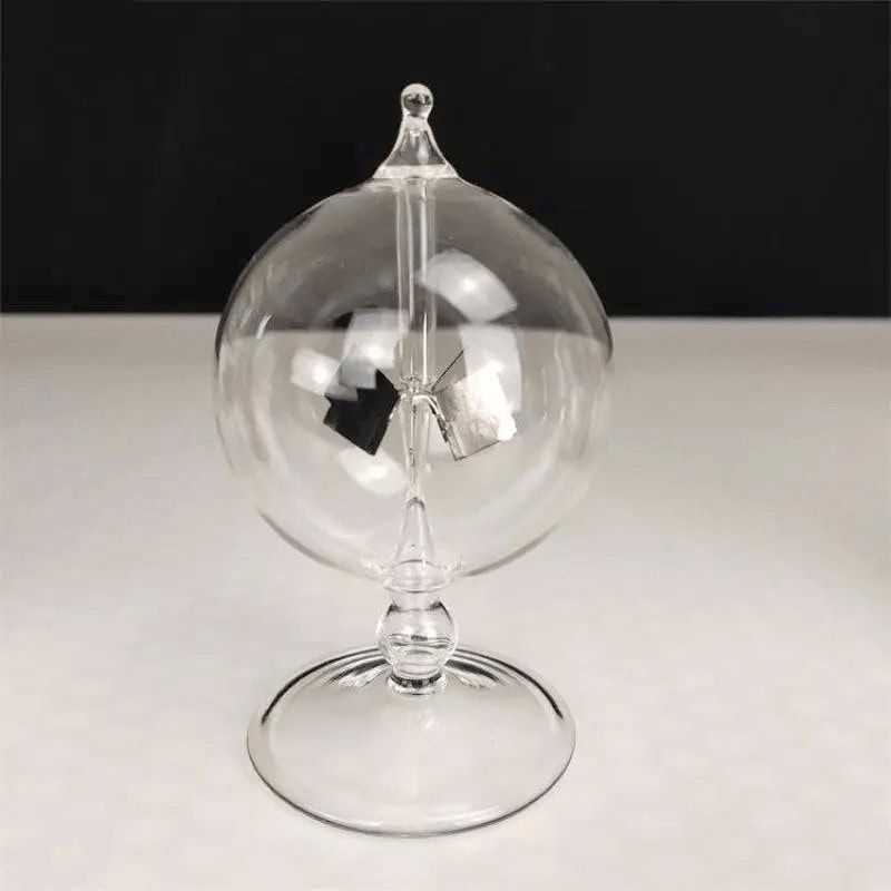 Transparent pendelboll i glas med hängande mekanism, elegant vetenskaplig dekoration, på svart och vit bakgrund.