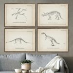 Fyra gamla illustrationer av dinosaurieskelett, inramade, hängande på väggen i ett modernt vardagsrum med grå soffa och grön växt.