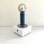Vetenskaplig demonstrationsanordning med en rostfri stålsfär, träbas och metallstöd, använd för att illustrera principerna för elektrisk fysik.
