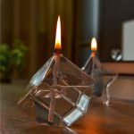 Glaspyramid med tända ljus, vetenskaplig och modern inredning, idealisk för en varm och elegant atmosfär.