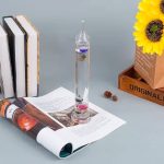 Vas i glas med färgad vätska, vetenskapsböcker och dekorationer, perfekt för vetenskaplig eller pedagogisk dekoration.