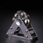 Pyramid av metallkulor i balans på en metallbas, som illustrerar ett fysikaliskt fenomen eller vetenskaplig experiment.