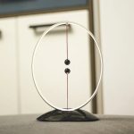 Newtonpendel i vetenskaplig inredning, som illustrerar fysik med två sfärer hängande i en cirkulär ram, perfekt för kontors- eller utbildningsinredning.