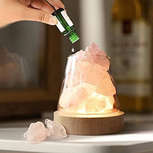 Pyramid av rosa saltkrystaller med flaska eterisk olja, vetenskaplig dekoration för hemmet eller kontoret.