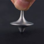 Liten Foucault-pendel i glänsande metall, hålls av ett finger, som illustrerar rotation för vetenskaplig demonstration.