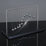 Newtonpendel i metall med hängande kulor, vetenskaplig dekorationsobjekt för kontor eller vardagsrum.