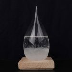 Transparent glasvas med klart vätska, placerad på en naturlig träsockel, som framhäver en elegant och minimalistisk design.