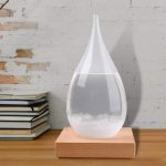 Glasflaska i form av en vattendroppe fylld med klart vatten, placerad på en träbas, elegant vetenskaplig dekoration för inomhusbruk.