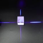 Transparent glaslaserhållare med blått ljus, projicerar ljusa linjer på en svart yta, vilket skapar en futuristisk och vetenskaplig visuell effekt.