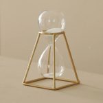 Tidsbärare i glas med gyllene ram, elegant och modern vetenskaplig dekoration, idealisk för älskare av industriell design och vetenskapsinspirerade dekorationsobjekt.