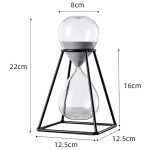 Dekorativ sandur i glas med svart metallram, mäter 22 cm i höjd, 8 cm i diameter, perfekt för vetenskaplig eller modern dekoration.