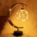 Dekorativ taklampa i form av en måne med en glasboll som innehåller en ljusslinga, idealisk för en originell och varm inredning.