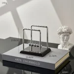 Newton-hänge i metall, inspirerat av det berömda Newtons kulexperiment, perfekt för kontors- eller hylldekoration med en vetenskaplig och modern stil.
