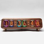 Vintage klocka med färgglada lysande tuber som visar tiden 18:36, monterad på en träbas, retro och dekorativ stil för en originell inredning.