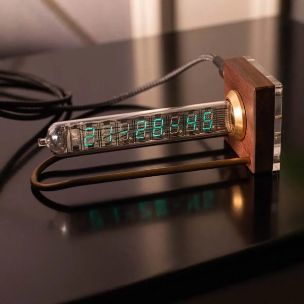 Vintage Nixie-rörklocka som visar tiden 21:28:45, med retrodesign och trähölje, placerad på en mörk yta.