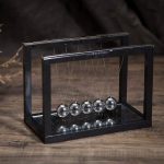 Svart Newton-pendel i metall, vetenskapligt experiment som illustrerar energins bevarande.