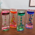 Transparent glasvas med rosa, orange, gröna och blå färgglada bubblor, idealisk för vetenskaplig eller modern inredning.
