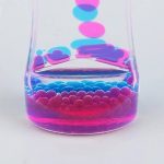 Burkar med färgglad vätska med svävande bubblor och droppar, som illustrerar ett vetenskapligt experiment eller en innovativ dekoration.