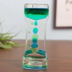 Transparent glasvas med grön vätska och dekorativa bubblor inuti, vilket skapar en intressant och modern visuell effekt.