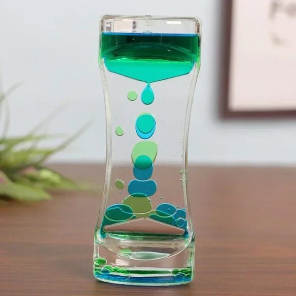 Transparent glasvas med grön vätska och dekorativa bubblor inuti, vilket skapar en intressant och modern visuell effekt.
