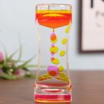 Transparent glasvas med färgglad rosa och gul vätska, med dekorativa bubblor som svävar inuti, vilket skapar en attraktiv och modern visuell effekt.