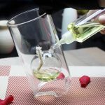 Vetenskapligt experiment med grönt vätska i ett glas, hällt från en pipett, på en rutig röd och vit duk.