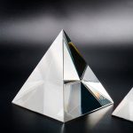 Optisk glaspyramid med reflekterande ytor, använd som dekorativt eller vetenskapligt objekt, på svart bakgrund.