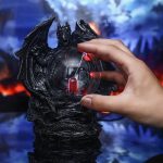 Draknyckelring i svart resin med inbyggd lysande glob, perfekt för dekoration eller som en originell accessoar. Detaljerad och mystisk design, idealisk för vetenskaps- och fantasientusiaster.