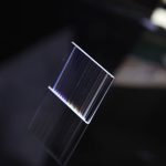 Transparent plexiglasskiva med ljusreflexer, används för vetenskapliga experiment eller som ett modernt dekorationsobjekt.