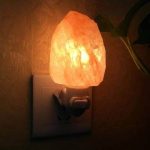 Upplyst Himalaya saltlampa, ansluten till ett eluttag, som skapar en varm och lugnande atmosfär. Perfekt för inredning eller avkoppling.