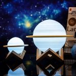 Dekorativ lampa i form av en planet med trästativ, idealisk för rymninspirerad inredning.