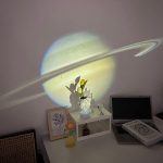 Saturnus projicerad på väggen med skugga av växter och kontorsdekorationer.