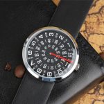 Klocka med unik display med svarta siffror och vit bakgrund, svart läderarmband, visar timmar, minuter och sekunder, modern och elegant design.