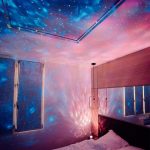 Projektion av stjärnor och galaxer på taket och väggarna i ett rum, vilket skapar en kosmisk, avslappnande och sagolik atmosfär.