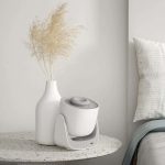 Vit vas med torkade växter och en aromaterapidiffusor på ett stentabell, minimal och elegant dekoration för ett modernt hem.