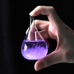 Laboratorieflaska i glas som innehåller en lysande lila vätska, hålls av en hand, som illustrerar vetenskap och vetenskaplig dekoration.
