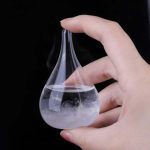 Glaspipett som innehåller en sprayad vätska, hålls av en hand mot en svart bakgrund, som illustrerar ett vetenskapligt experiment eller en laboratoriedemonstration.