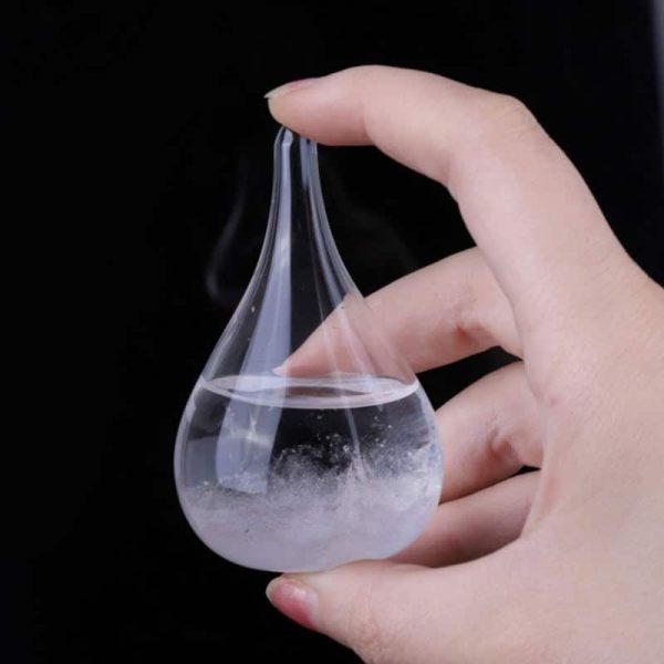 Glaspipett som innehåller en sprayad vätska, hålls av en hand mot en svart bakgrund, som illustrerar ett vetenskapligt experiment eller en laboratoriedemonstration.