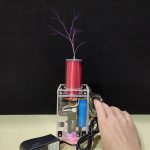 Miniatyr Tesla-spole med lila gnistor, LED-belysning och synliga elektroniska komponenter.