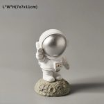 Astronautfigur i vit resin med glänsande hjälm, placerad på en stenig bas. Idealisk för vetenskaplig eller tematisk dekoration, som ger en touch av rymdäventyr till ditt hem.
