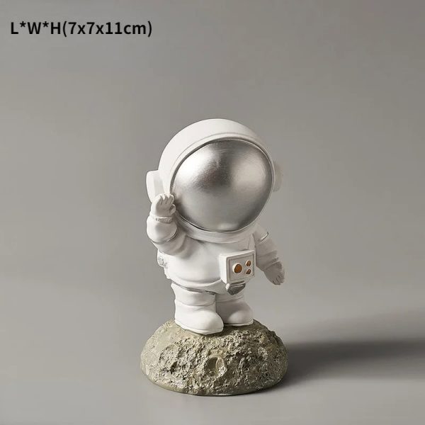 Astronautfigur i vit resin med glänsande hjälm, placerad på en stenig bas. Idealisk för vetenskaplig eller tematisk dekoration, som ger en touch av rymdäventyr till ditt hem.