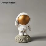 Dekorativ astronautfigur med gyllene hjälm, idealisk för inredning eller som samlarobjekt med rymdtema.