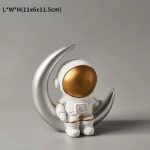 Astronautfigur med gyllene hjälm på en silverfärgad halvmåne.