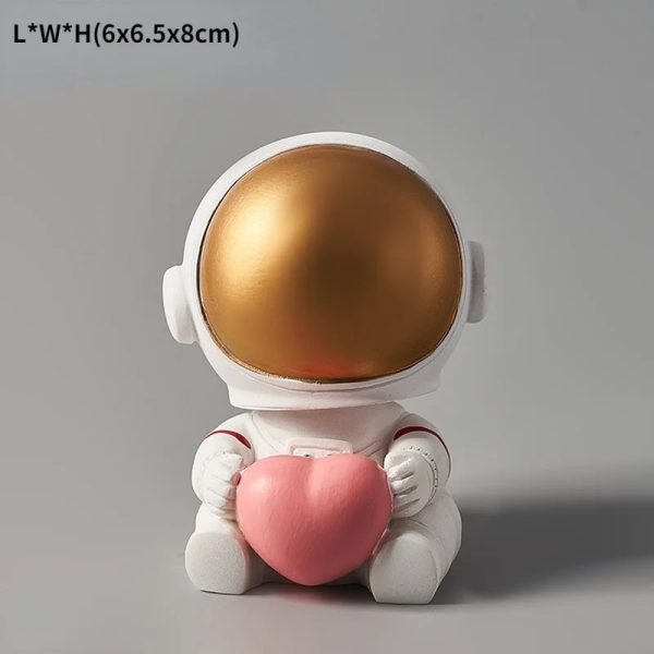 Söt astronautfigur som håller ett rosa plyshhjärta, idealisk för vetenskaplig och lekfull dekoration.
