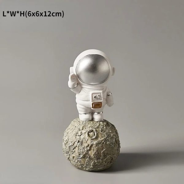 Astronautfigur i dekoration, som föreställer en kosmonaut i rymddräkt på en månlandskap, idealisk för tematisk vetenskaplig dekoration.