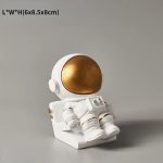 Dekorativ astronautfigur i guld och vitt, idealisk för inredning eller som samlarobjekt med rymdtema.