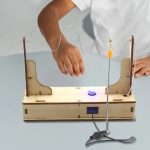 Vetenskapligt experiment med ledningar, glödlampa och trästöd för att lära sig om elektricitet.