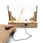 Uppställning av ett elektriskt experiment med en strömgenerator, en spole och en LED, som illustrerar en enkel krets för vetenskaplig demonstration.