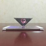 Lysande 3D-hjärta svävande över en smartphone, konstverk med ljuseffekter och modern teknik.